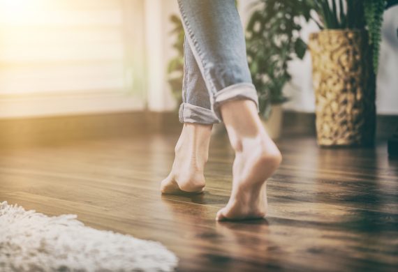 Bare foot woman walking across a wooden floor