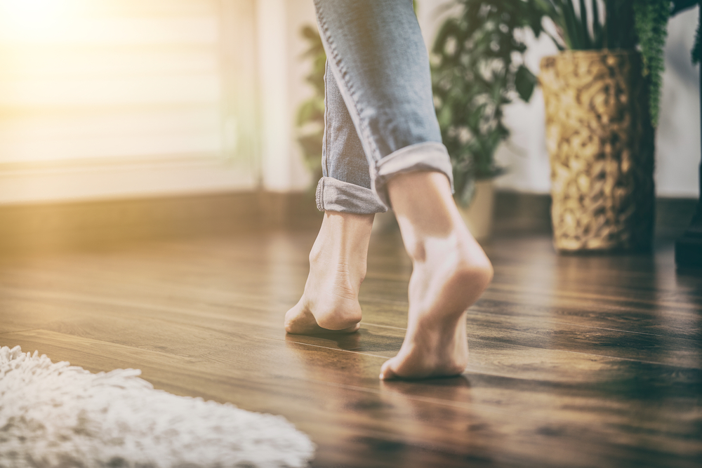 Bare foot woman walking across a wooden floor