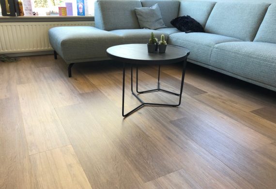 laminate flooring with a blue sofa and small table