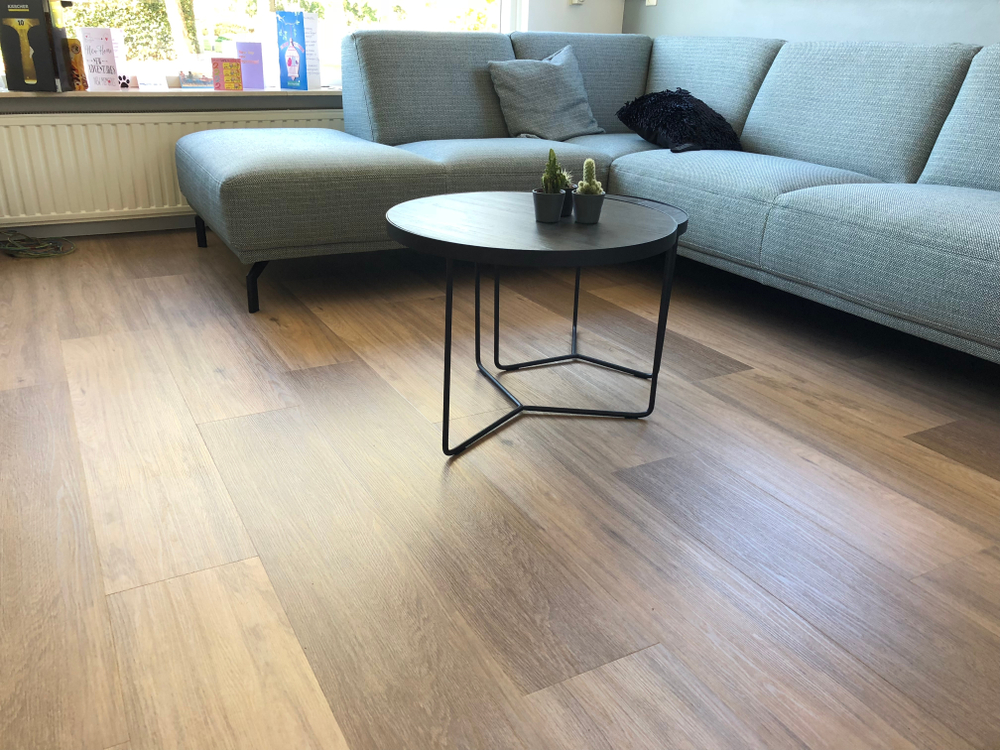 laminate flooring with a blue sofa and small table